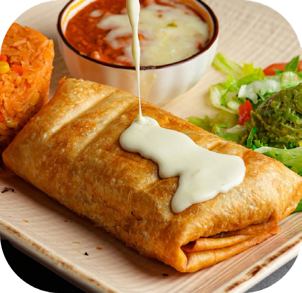 A golden fried chimichanga topped with white queso, with rice, salad and guacamole